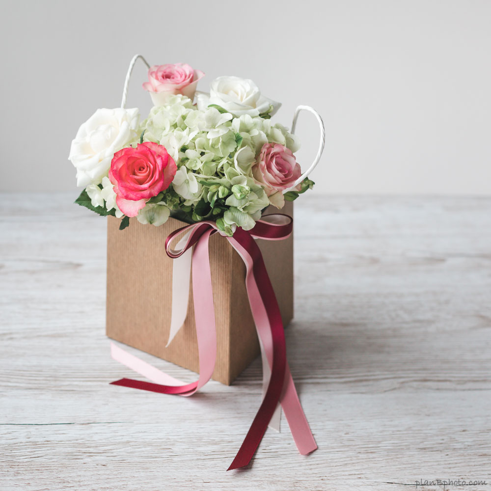 roses and hydrangea flowers in a box with a bow